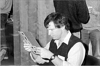 Black and white photograph of a young Brian Staskawicz studying some photographic slides