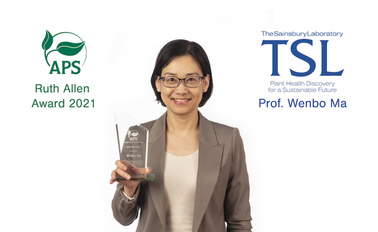 Photograph of Wenbo Ma against a white background with the American Phyopathological Socitety and Sainsbury Laboratory Logos. Wenbo is holding the Ruth Allen Award trophy in her right hand.